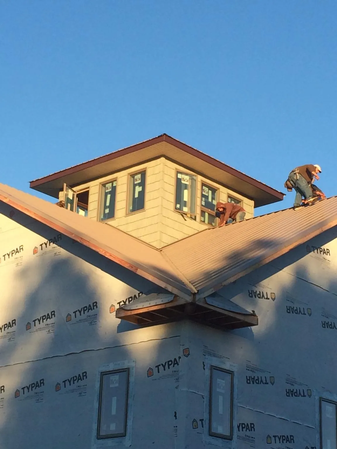Roofers working around a rooftop cupola on a new metal roof at sunset — Roof Waterproofing in Portsmouth by Roofing Brothers